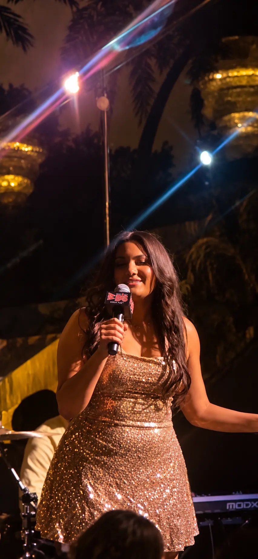 Angelina Thompson in a gold sequined dress performing on stage at LÉLÉ