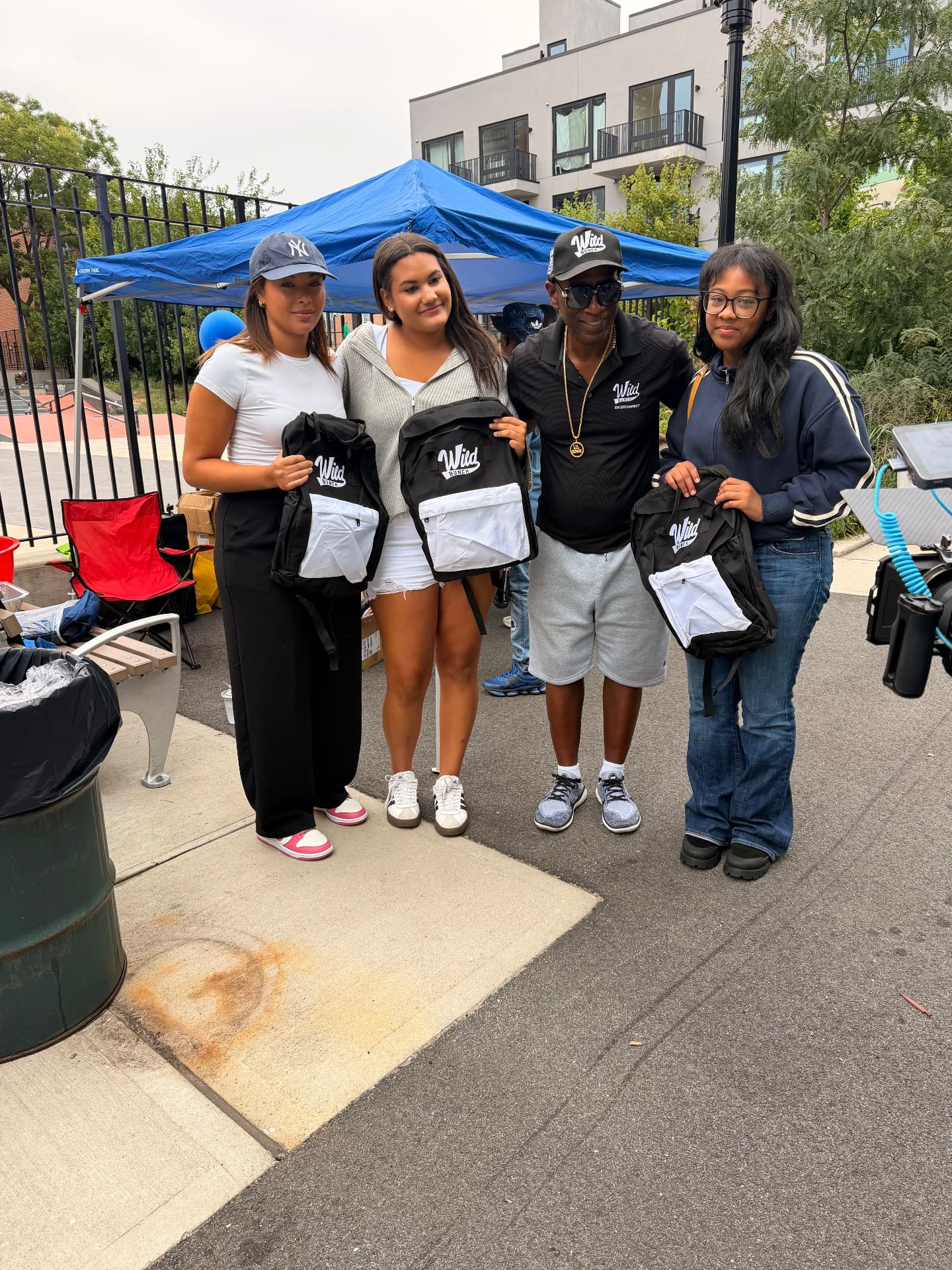 Angelina Thompson, Aksana Antonius and Donny Smallwood Jr. holding Wild Bunch book bags at the 7th Annual Community Event in Brooklyn
