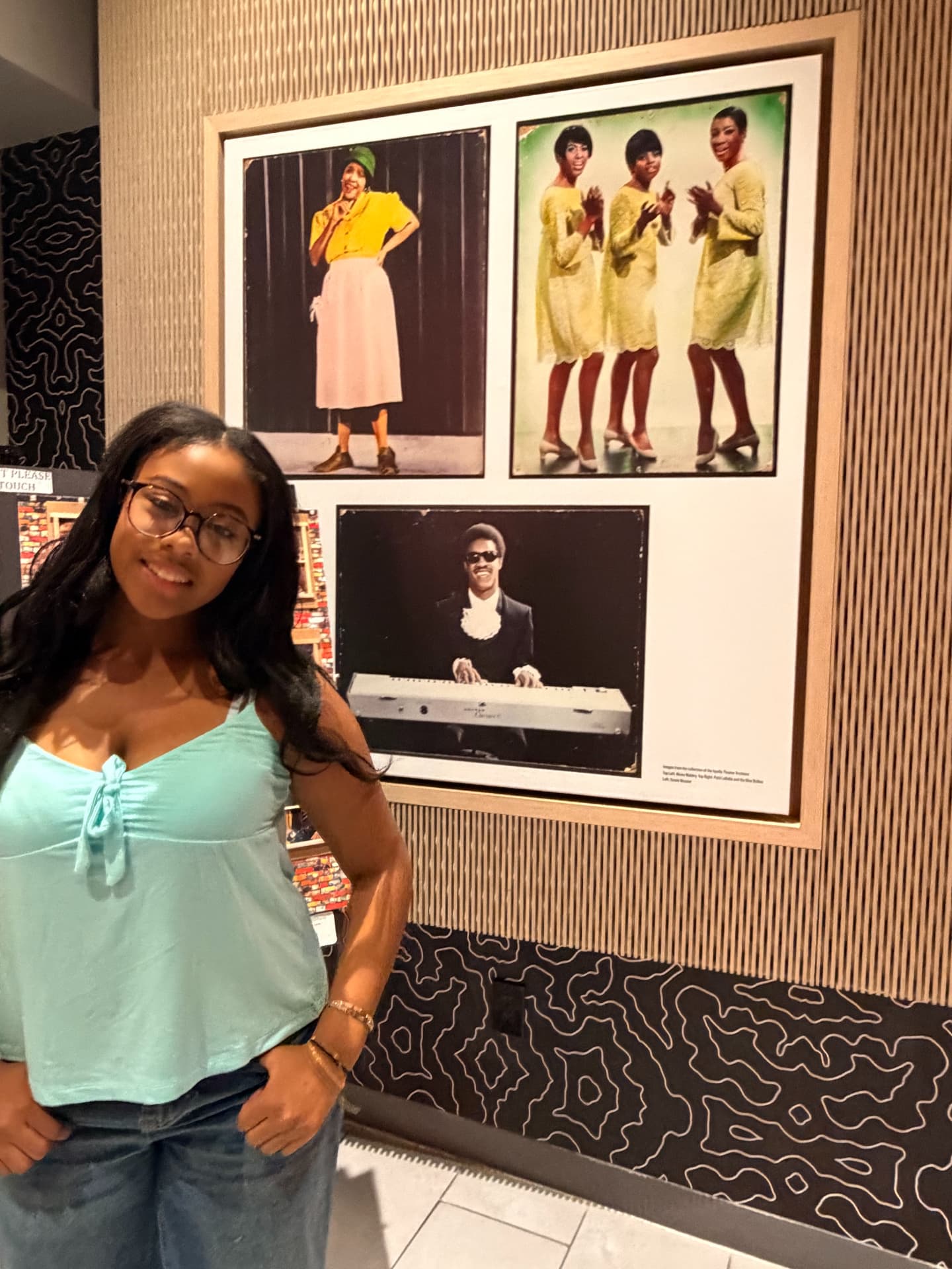 Aksana Antonius in a turquoise top beside the Apollo's historic artist photography display